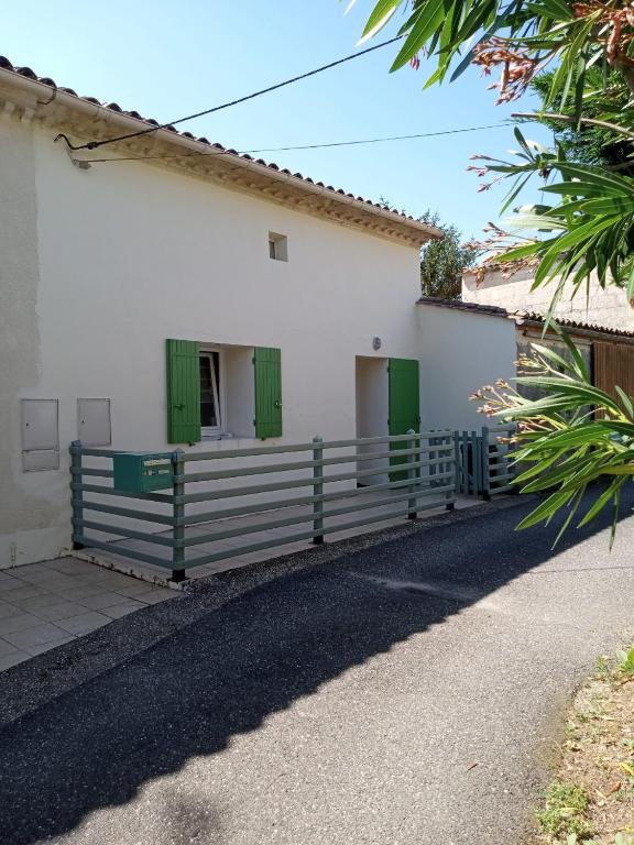 un bâtiment blanc avec des portes vertes et une clôture dans l'établissement Gîte du Plisseau, à Le Rigalet