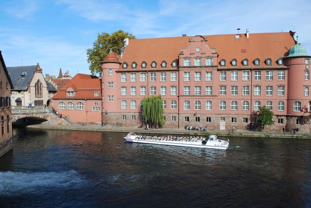 un bateau dans une rivière devant un bâtiment dans l'établissement Petite France, Studio de charme vue sur l'Ill, à Strasbourg