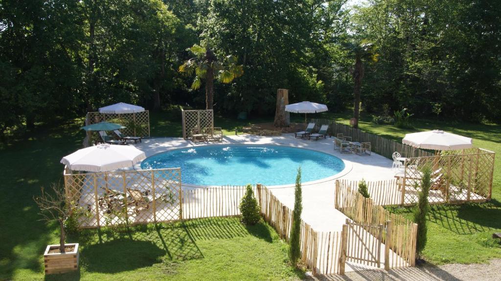 a swimming pool with umbrellas and a fence around it at Armagnac in Moncaut