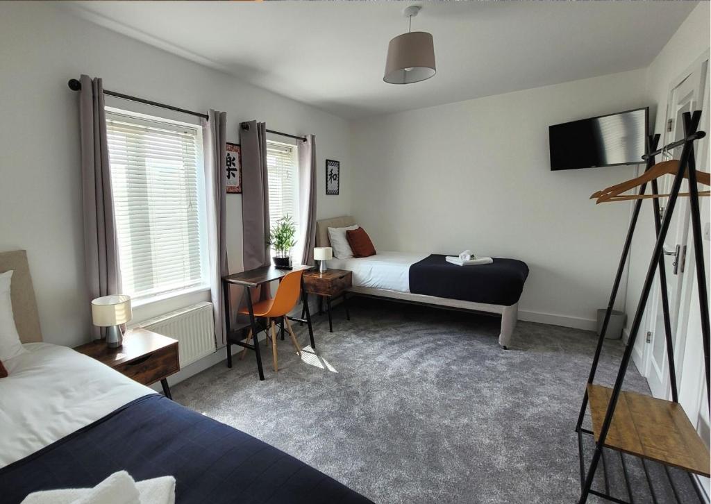 una camera d'albergo con letto, scrivania e letto di 4 Bedroom House By Your Lettings Short Lets & Serviced Accommodation Peterborough With Free WiFi,Netflix and more a Peterborough