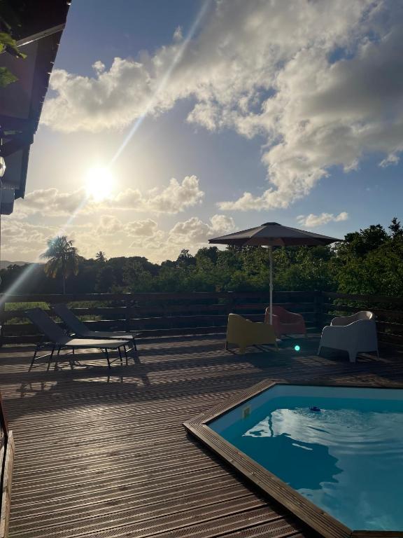 a deck with a pool and chairs and an umbrella at Withsun in Saint-Louis