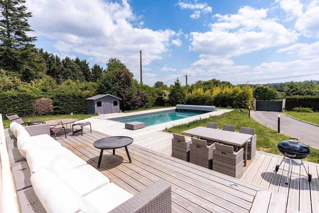 une arrière-cour avec une piscine et une terrasse en bois dans l'établissement Maison à la campagne avec piscine chauffée proche Deauville, à Saint-Étienne-la-Thillaye