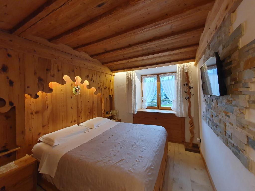 a bedroom with a bed and a tv on a wall at Daniela Apartment in Cortina dʼAmpezzo