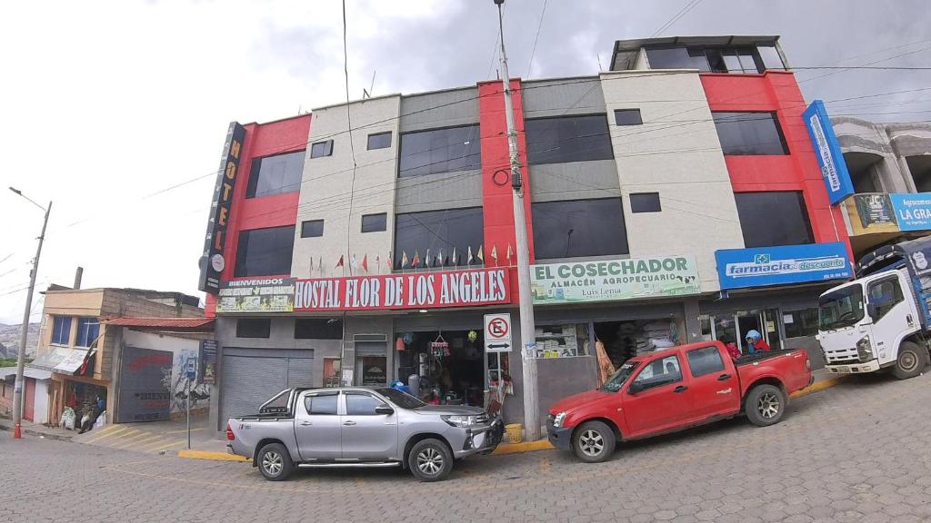 due auto parcheggiate di fronte a un edificio di Hostal Flor de los Ángeles a Guamote