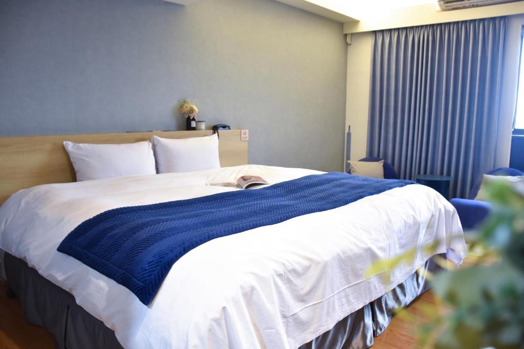 Talmud Hotel Gongyuan في تايتشونغ: سرير عليه بطانيه زرقاء وبيضاء