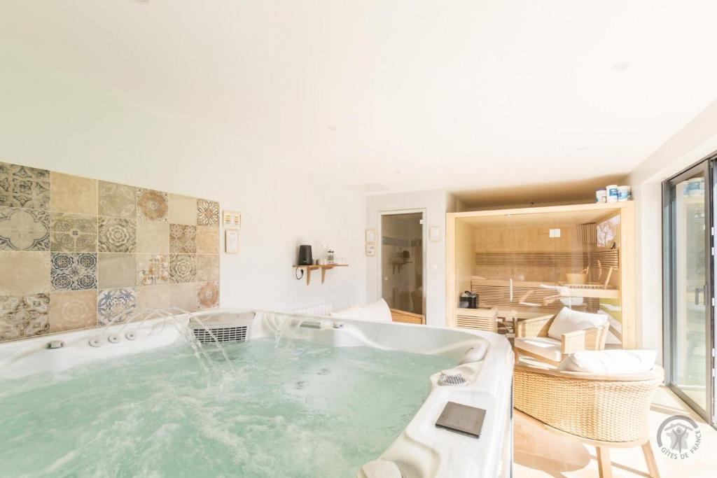 eine große Badewanne in einem Zimmer mit Wohnzimmer in der Unterkunft Le Jardin De Marie in Pontorson