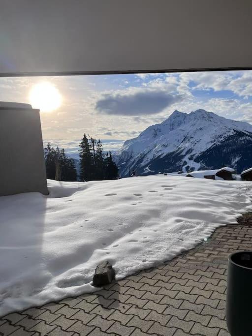 une cour enneigée avec une montagne en arrière-plan dans l'établissement 2 pièces 4-6 personnes rénové avec parking couvert, 100m des pistes, à Montvalezan