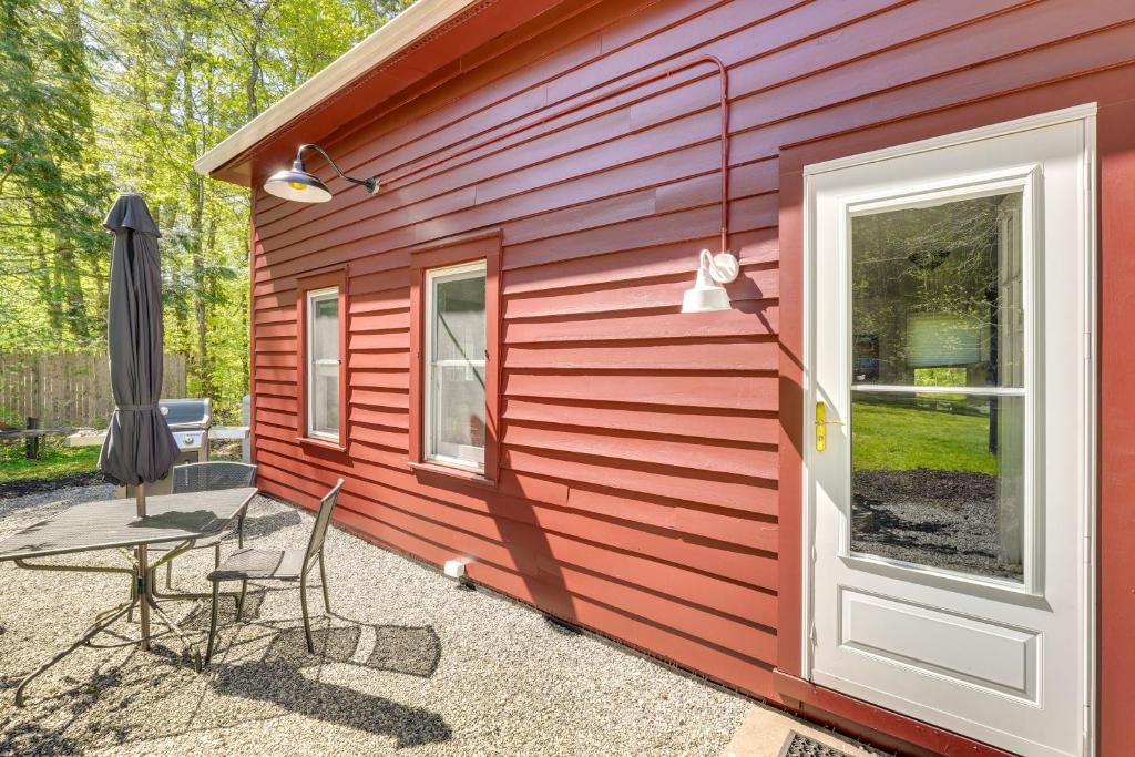a red building with a table and chairs and an umbrella at UpdatedandPet-Friendly Cabin By Hikes and Woodstock! in Bearsville