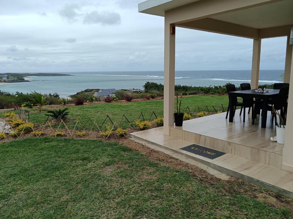 - une table à manger sur une terrasse couverte offrant une vue sur l'océan dans l'établissement La Residence Emmaüs, à Rodrigues Island