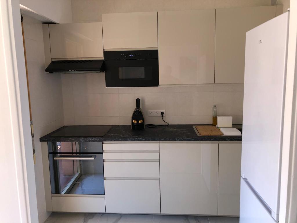 - une cuisine avec des placards blancs et une bouteille de vin dans l'établissement JUAN LES PINS CENTRE T1 Bis 313, à Antibes