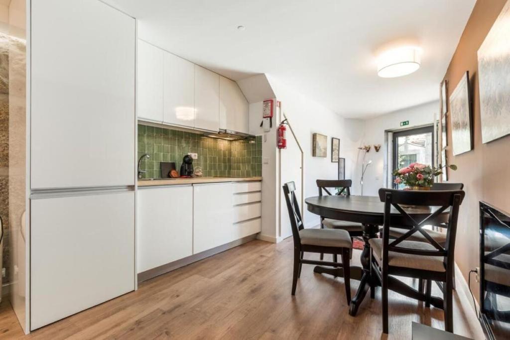 cocina y comedor con armarios blancos y mesa en Cute 1-bedroom next to Douro River, en Oporto