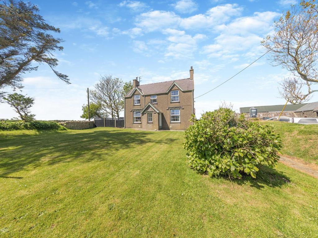 a large house on a grassy field with a tree at Porthysgaden in Twdweiliog