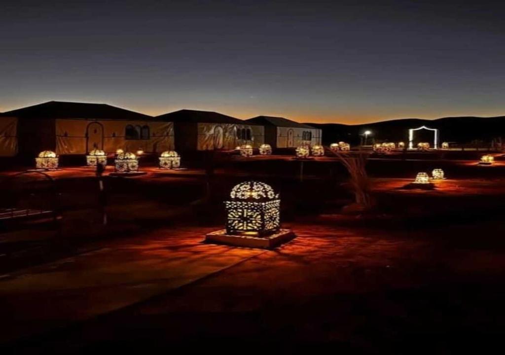 Najma Luxury Camp في مرزوقة: مجموعة من الأضواء في الفناء في الليل