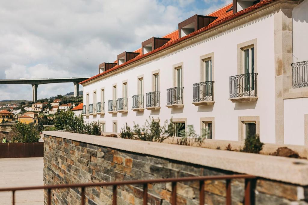 un edificio blanco con ventanas y un puente en el fondo en Torel Quinta da Vacaria - Douro Valley en Peso da Régua