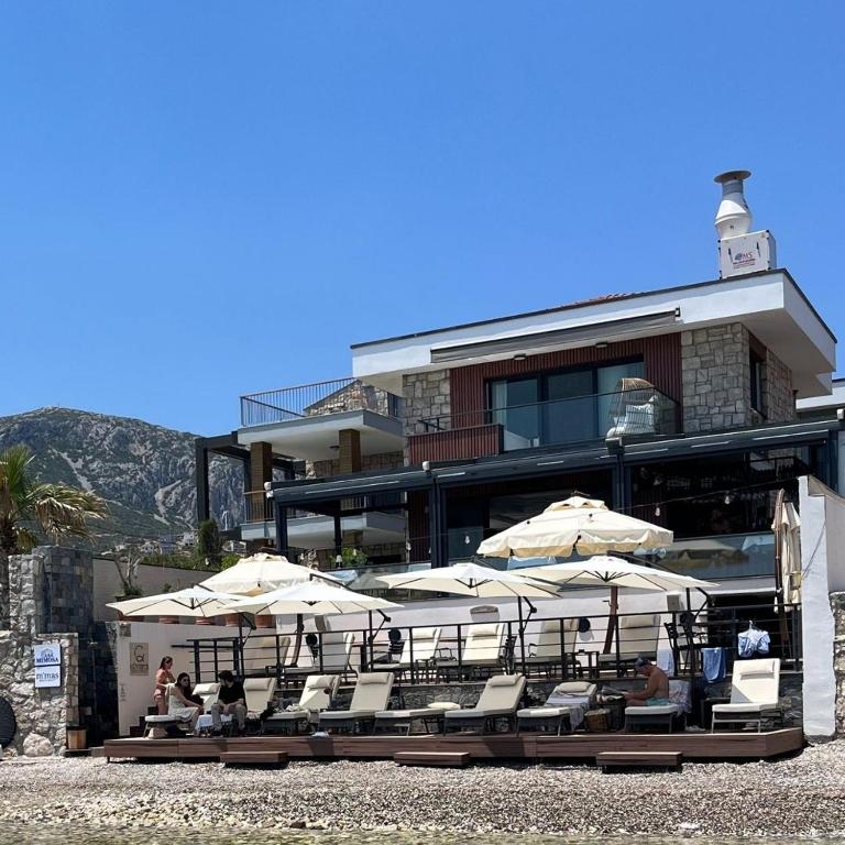 a group of chairs and umbrellas in front of a building at Casa Mimosa Hotel in Karaburun
