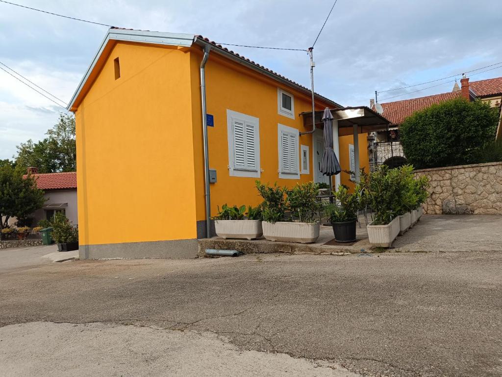 una casa amarilla con macetas delante de ella en Holiday house Dalinda, en Dražice