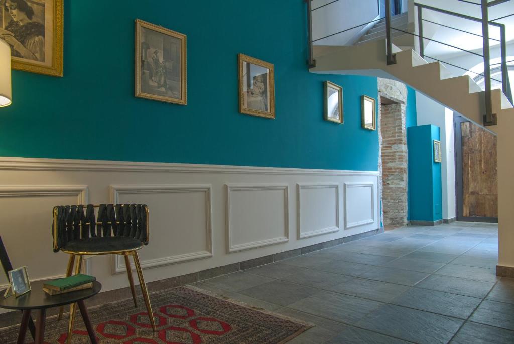 a hallway with blue walls and a chair and a staircase at Bookbreakfast in Terme Vigliatore