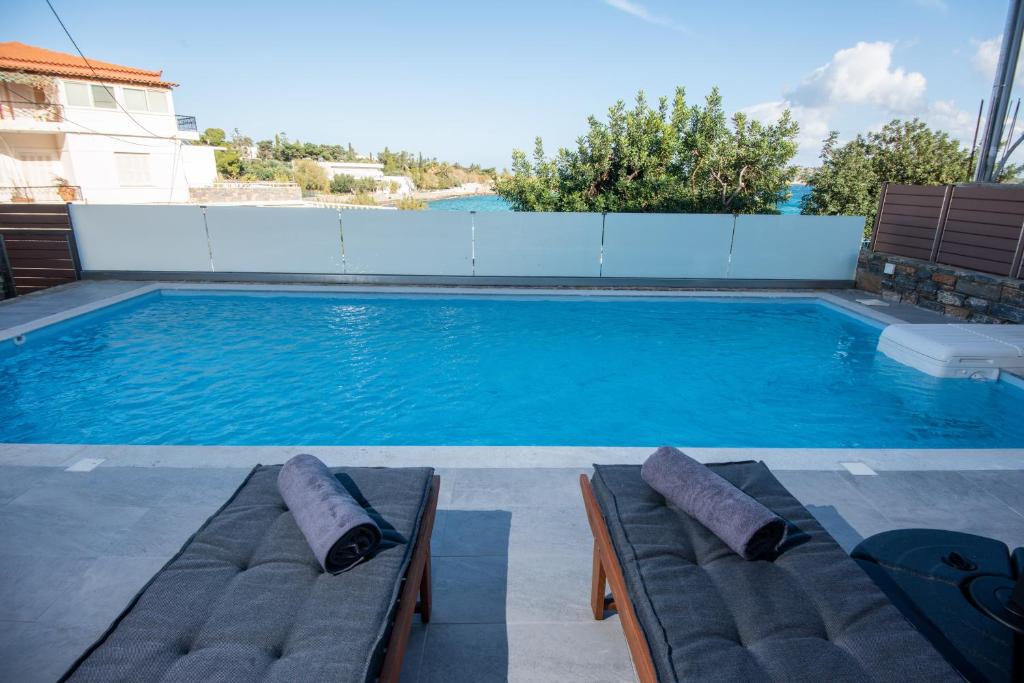 una piscina con due lettini di fronte ad essa di Ammos Lux Apartments Crete ad Ágios Nikólaos