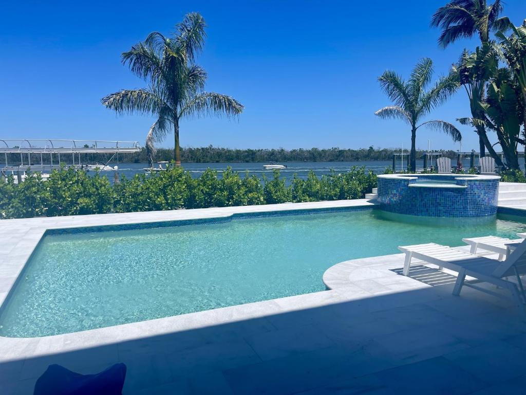 uma piscina com uma mesa e um banco e palmeiras em 3891 Bayside em Fort Myers Beach