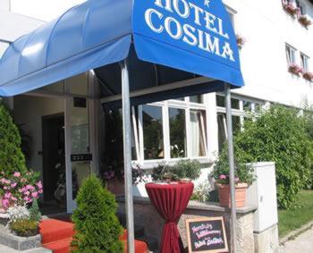 a store with a blue umbrella in front of a building at Hotel Cosima in Vaterstetten
