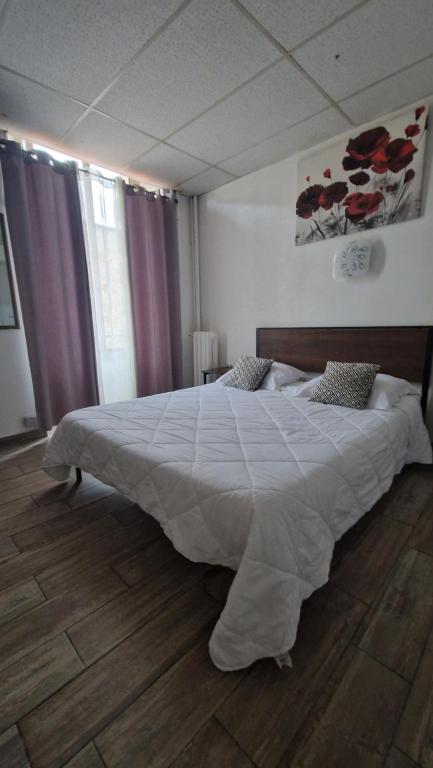 Hôtel du Nord في كان: غرفة نوم بسرير كبير مع لحاف أبيض