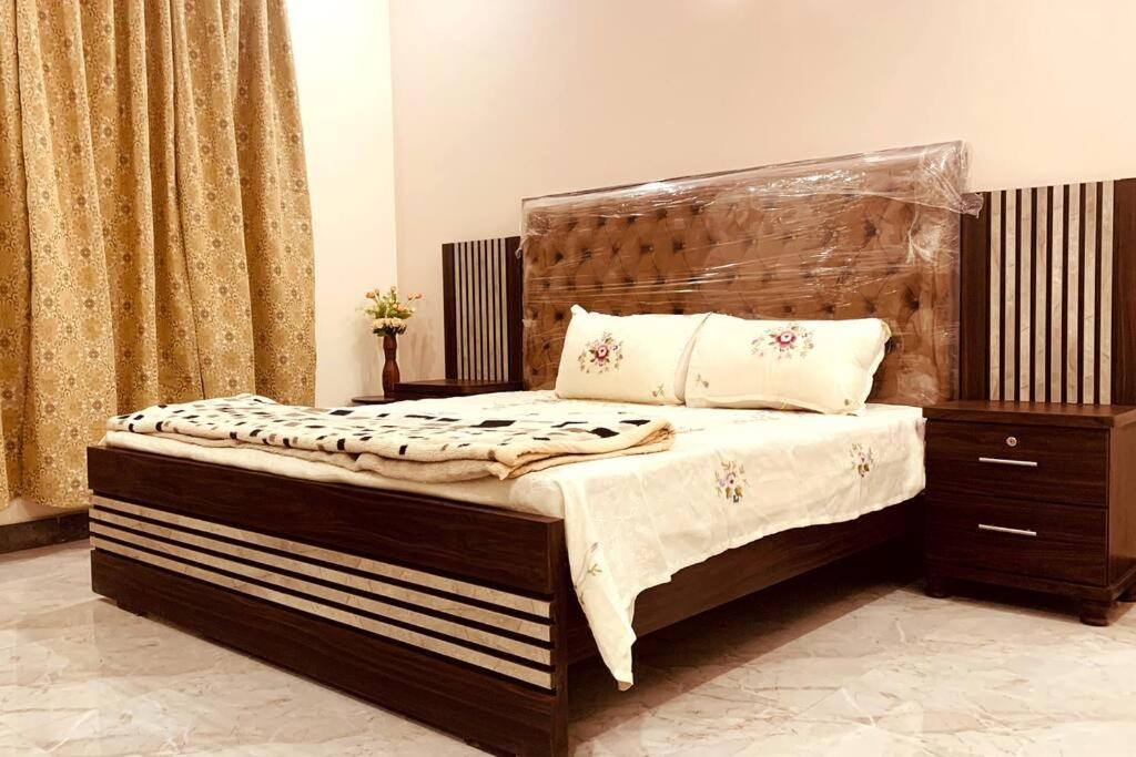 a bed with a wooden headboard in a bedroom at Exotic Hill View Stay in Karachi