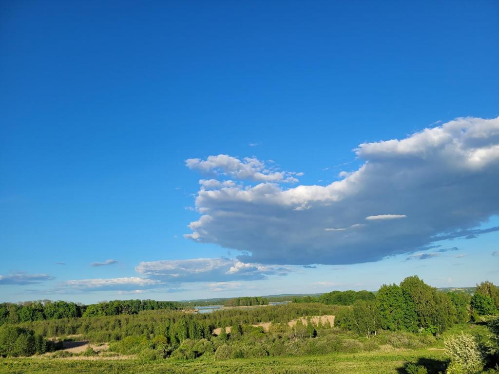 un cielo azul con nubes sobre un campo verde en Wyskok 1 - dom z widokiem, en Srokowo