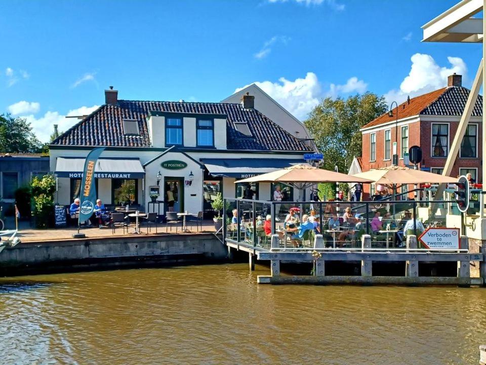 ein Restaurant auf einem Dock neben einem Wasserkörper in der Unterkunft Hotel Restaurant It posthus in Birdaard
