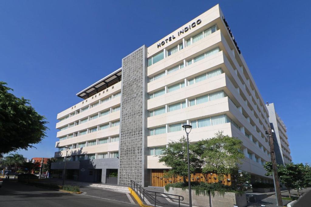 Un alto edificio bianco con un cartello sopra di Hotel Indigo Guadalajara Expo, an IHG Hotel a Guadalajara