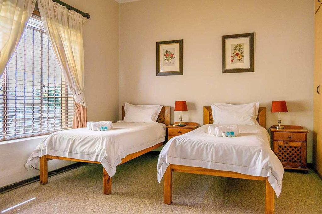 1 dormitorio con 2 camas y ventana en RIETONDALE LODGE en Pretoria
