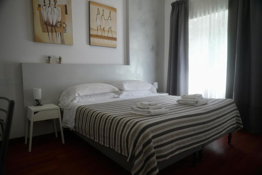a bedroom with a bed with a striped blanket and a window at Casa Mia Guesthouse in Rome