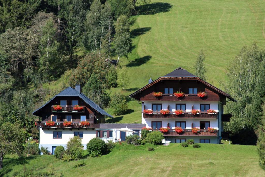 dos casas en una colina con flores en sus ventanas en Pension & Appartements Ronacherhof en Bad Kleinkirchheim
