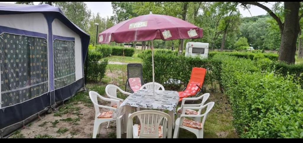 una mesa con sillas y una sombrilla en un patio en Nap kemping 84 parcella en Fonyód