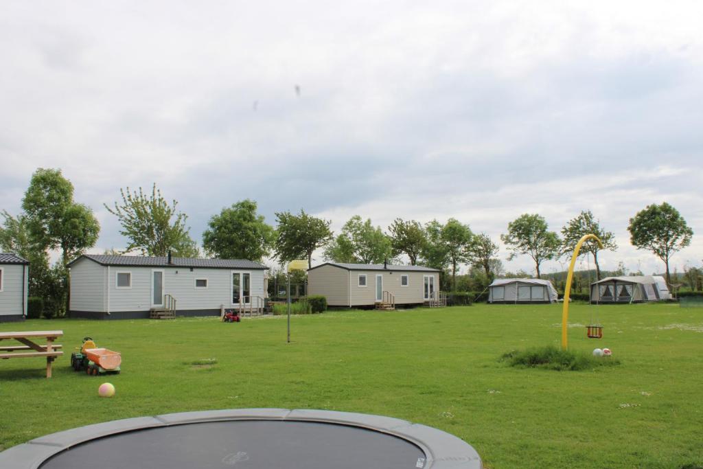 un gran patio con casas y un parque con parque infantil. en Minicamping Zonnehoek en Biggekerke
