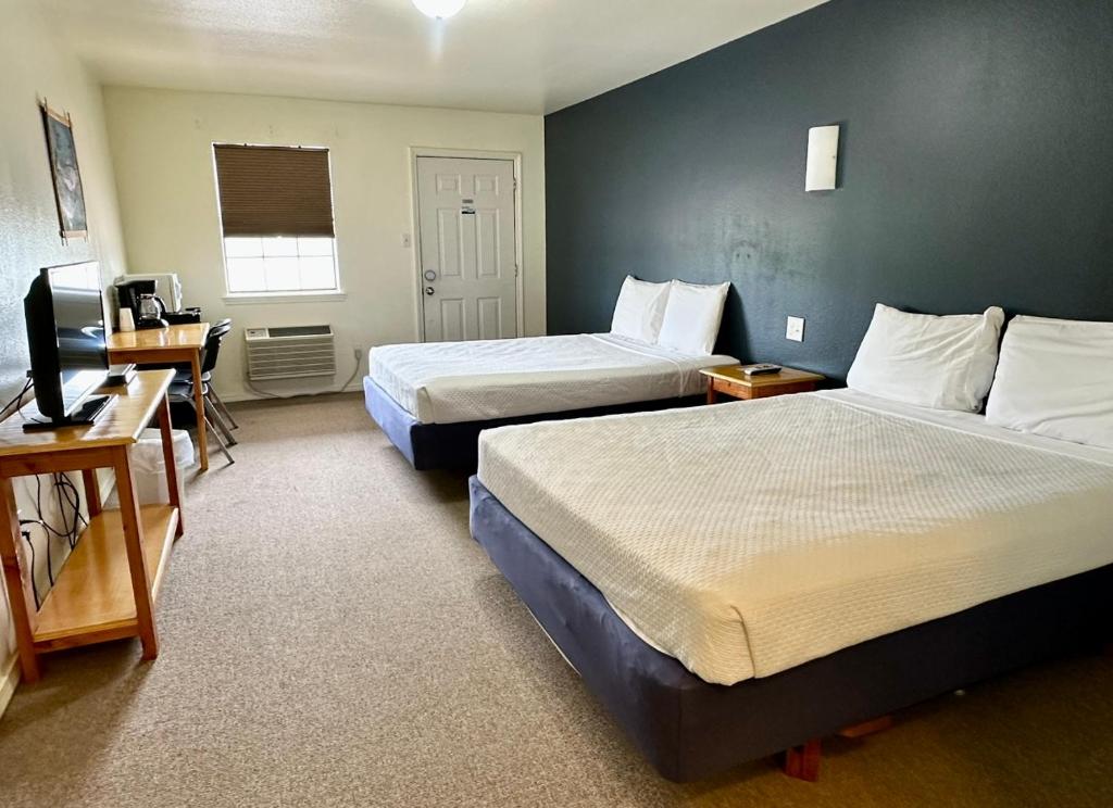 a hotel room with two beds and a television at Lakeside Motel, Cabins and RV in Kingston