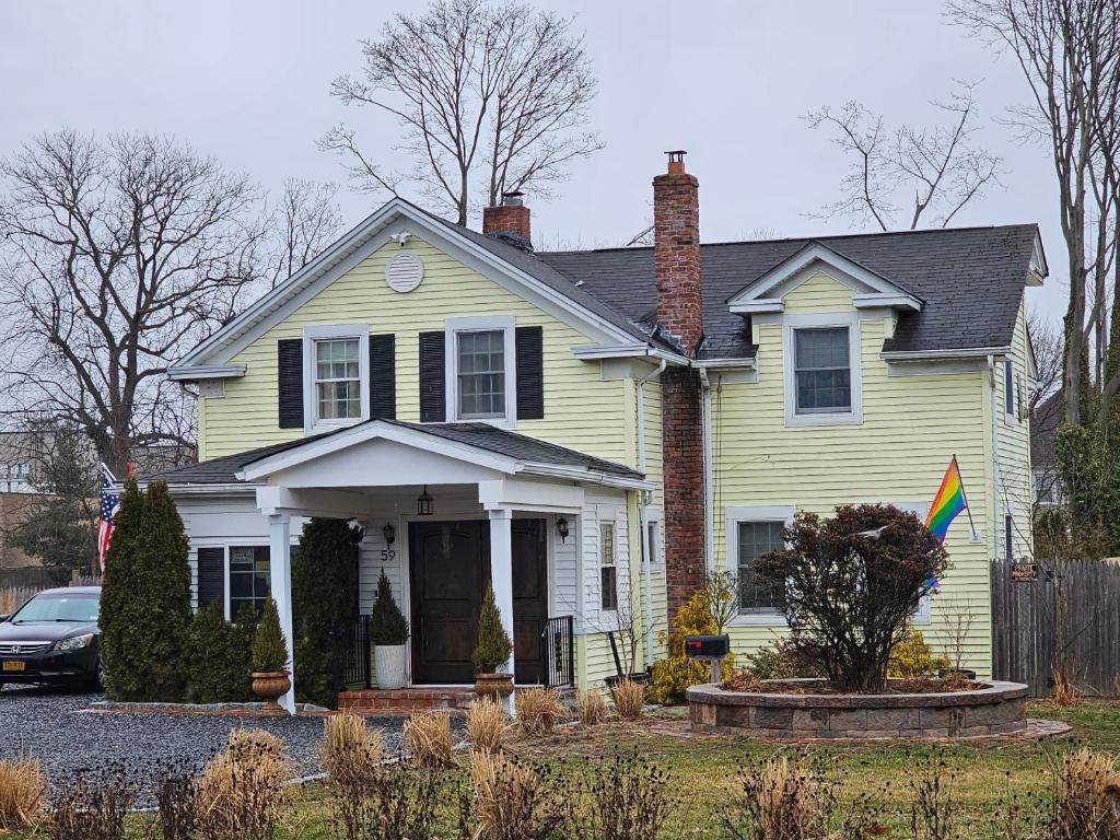 a yellow house with a flag in the front yard at Come As You Are Inn LLC 