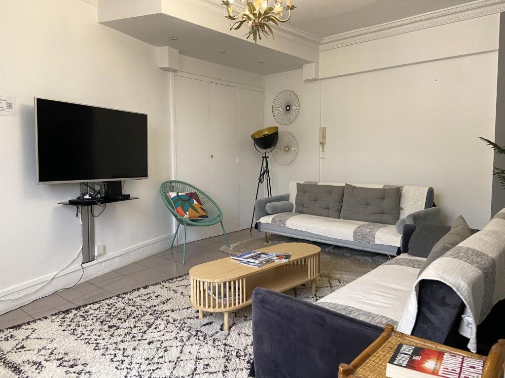 un salon avec un canapé et une télévision dans l'établissement L'appartement des Champs Elysées, à Paris
