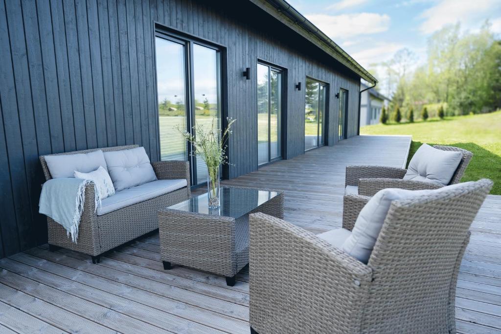 a porch with wicker chairs and a glass table at Private House with 4 Bedrooms and SAUNA near TARTU 
