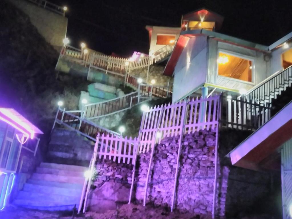 THE WONDERLAND COTTAGES & Cafe في ناركاندا: منزل به أضواء أرجوانية على الدرج في الليل