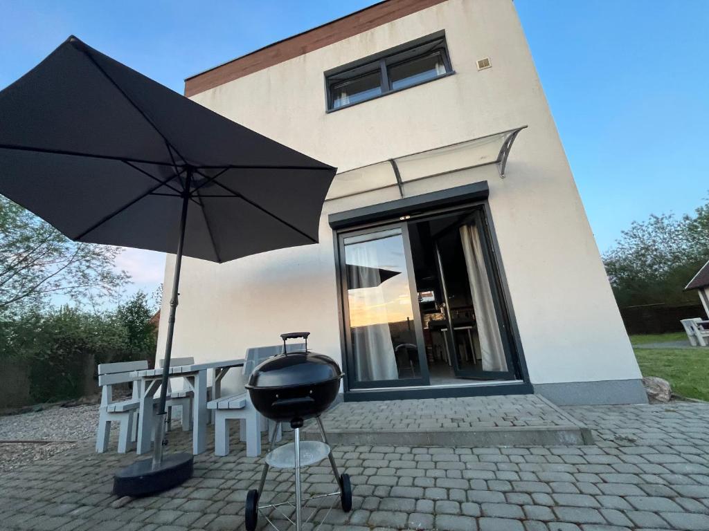 a grill and an umbrella in front of a building at Nemo - apartament, domek w Gaskach in Gąski