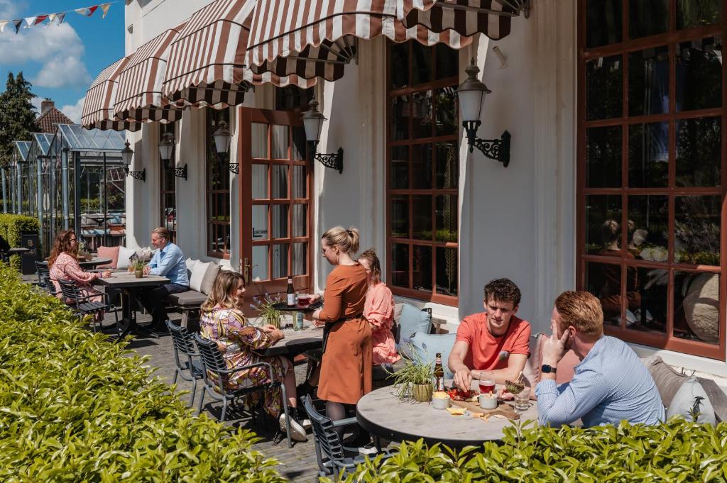 een groep mensen die aan een tafel op een patio zitten bij Boutique Hotel Restaurant BAL in Echteld