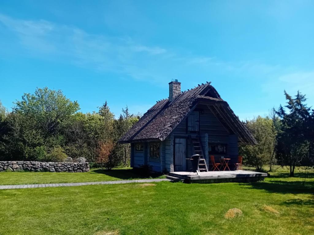 une petite maison dans un champ avec une pelouse dans l'établissement Romantiline saunamaja Pädaste lahe ääres, à Pädaste
