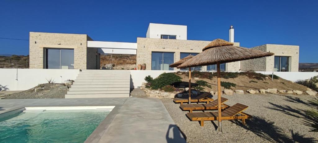 a group of chairs and an umbrella next to a swimming pool at Komos Beach Estate in Kalamaki