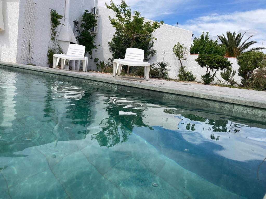- deux chaises blanches installées à côté de la piscine dans l'établissement PAULA, à Riumar