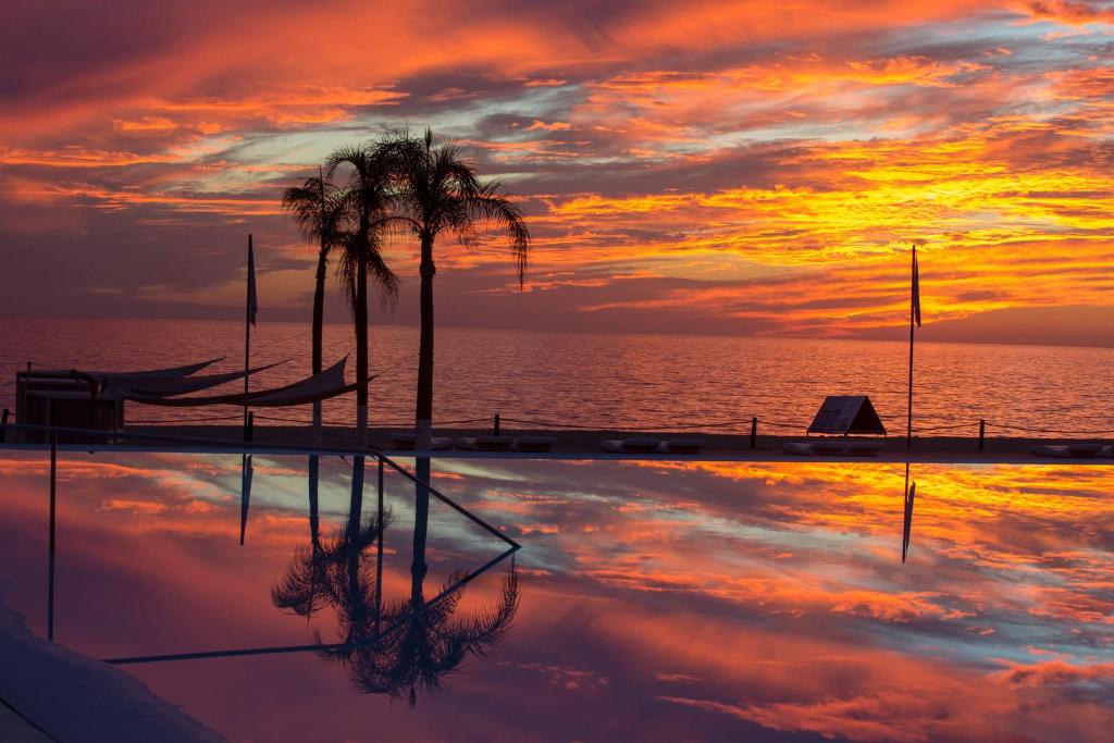 una piscina con palmeras y una puesta de sol en Suites @ Aria Ocean, en Nuevo Vallarta 