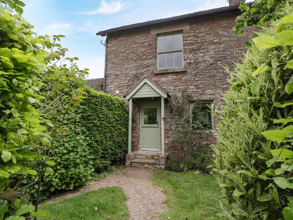 an old brick house with a green door at Woodlands Cottage in Leominster