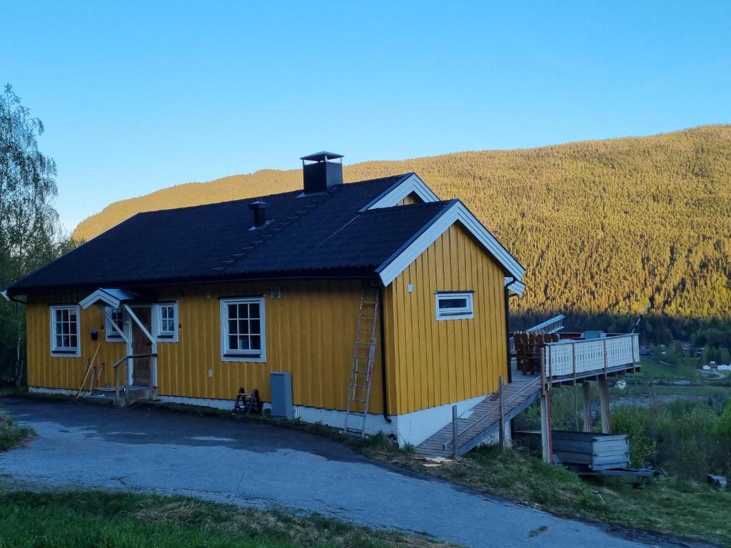 żółty dom z czarnym dachem na polu w obiekcie Solhaug w mieście Torpo