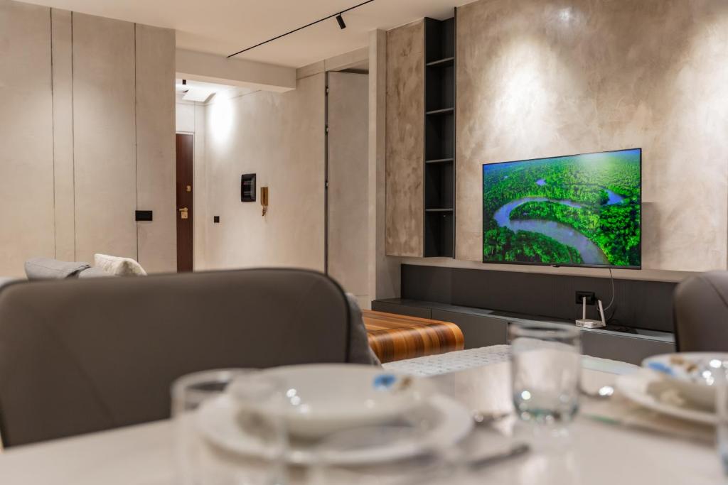 a dining room with a table and a flat screen tv at Cosmo Comfort in Tirana