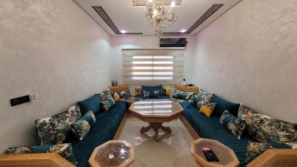 ein Wohnzimmer mit einem blauen Sofa und einem Tisch in der Unterkunft Bel appartement dans une résidence calme in Meknès