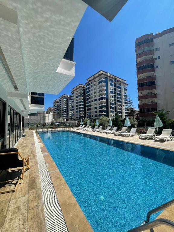 a large swimming pool with lounge chairs and buildings at SA Apartments! Mahmutlar, 300m to the Beach in Alanya